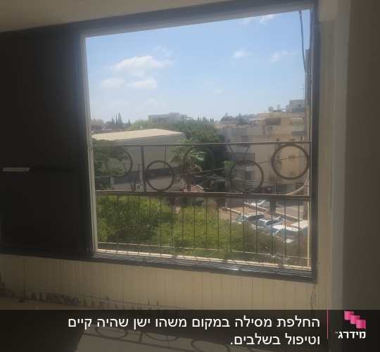 מרפסת עם חלון פתוח ונוף לבניינים ועצים